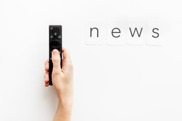News concept. TV remote in hand on white background top-down copy space