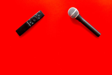 TV news concept. TV remote and microphone on red background top-down copy space