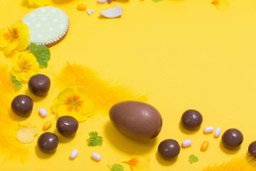 Easter yellow background with chocolatte eggs,    candy and spri