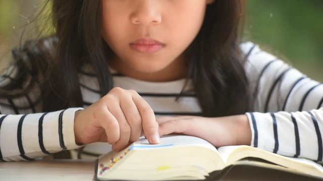 cute little asian girl in reading bible. hands holding on a holy bible. little child girl hands folded in prayer on a holy Bible for faith,spirituality and religion concept.