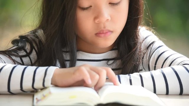 cute little asian girl in reading bible. hands holding on a holy bible. little child girl hands folded in prayer on a holy Bible for faith,spirituality and religion concept.