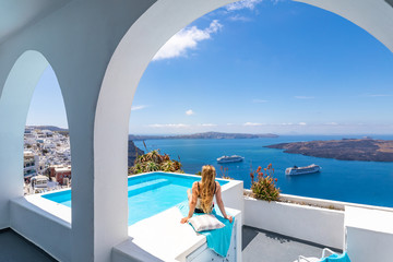 Luxury summer vacation background. Young woman on vacation at Santorini, women at the swimming pool looking out over the Caldera ocean of Santorini, Girl at the infinity pool Santorini Greece - obrazy, fototapety, plakaty
