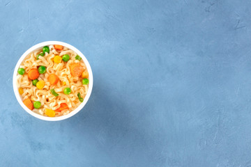 Ramen cup, instant soba noodles with vegetables in a plastic cup, top-down shot with a place for text