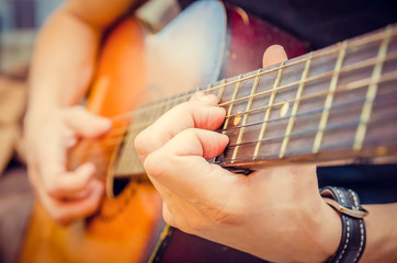Close-up of a guitarist's hand on an acoustic guitar. Guitar player's hand on the fretboard of an...
