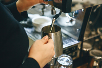 Fototapeta na wymiar Close-up of a barista preparing milk in a coffee machine for adding to coffee.