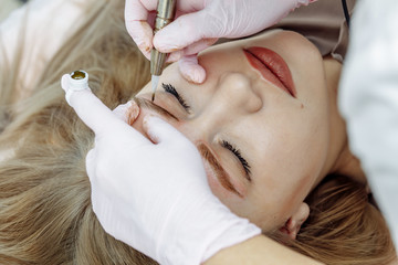 Permanent makeup, tattooing of eyebrows. Cosmetologist applying make up