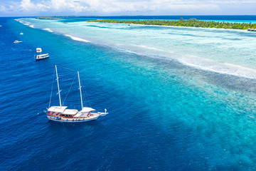 Fototapeta na wymiar Beautiful turquoise ocean water with boats on it top view aerial photo. Maldives island and sea, amazing aerial photo. Wonderful landscape scenery, exotic travel landscape, summer vacation, holiday