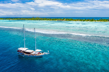 Beautiful turquoise ocean water with boats on it top view aerial photo. Maldives island and sea,...