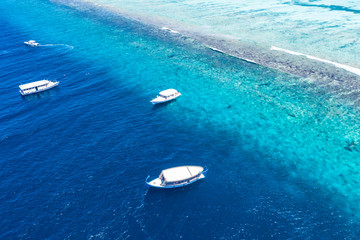 Beautiful turquoise ocean water with boats on it top view aerial photo. Maldives island and sea, amazing aerial photo. Wonderful landscape scenery, exotic travel landscape, summer vacation, holiday