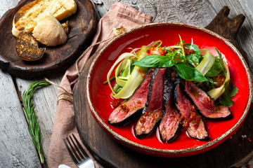 Warm salad with roast beef on a red plate. A dietary meal for a healthy diet