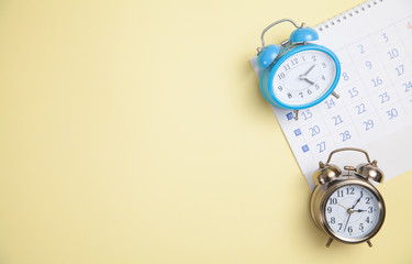 Alarm clocks with calendar on yellow background.