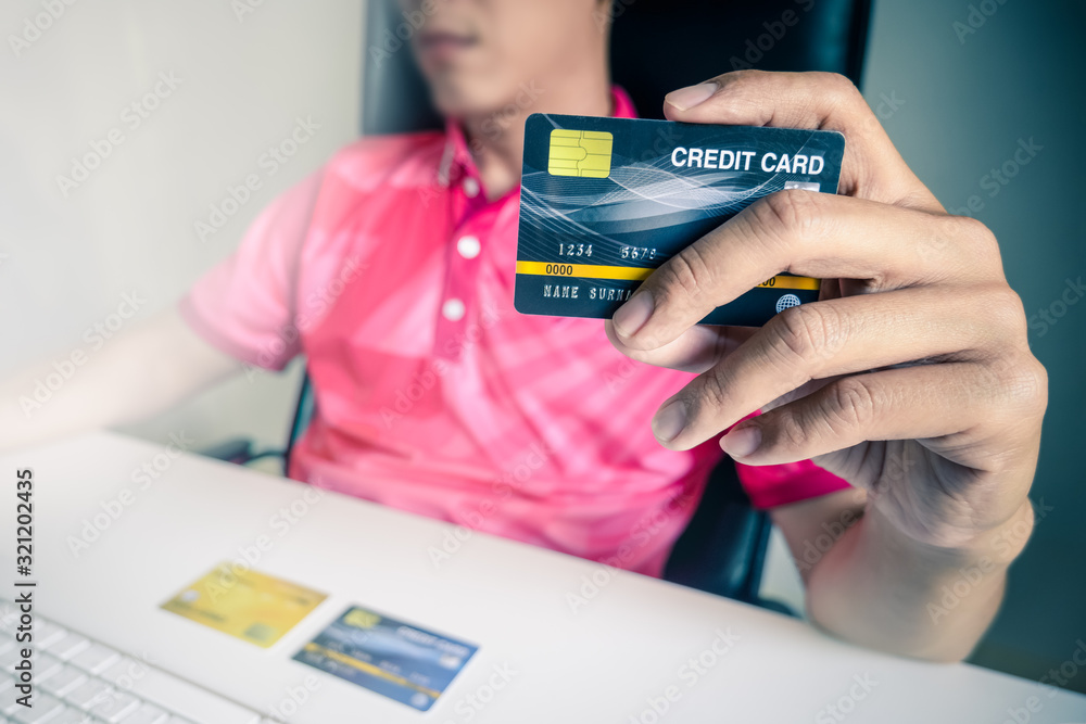 Poster man paying with credit cards on computer at home.