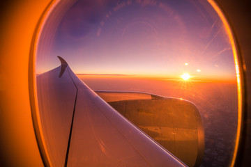 Sunset sky from the airplane window. View on the sunset and airplane wing from the inside