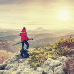Photographer with tripod and camera on cliff and thinking