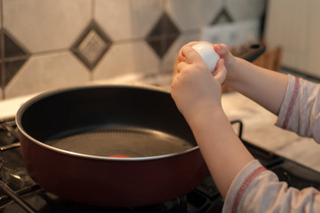 Fototapeta na wymiar Little girl cooks fried eggs in a pan