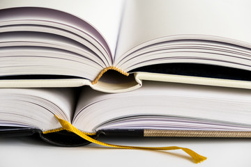 Opened blank hardcover books with ribbon bookmarks. Isolated closeup on a white background..