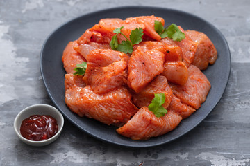 raw meat with spices on dark dish on ceramic background