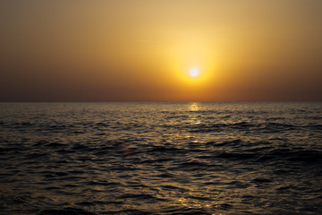 Obraz premium a beautiful sunrise on the seashore. the waves of the sea hit the rocks scattering water. the sun is making its appearance in a new day