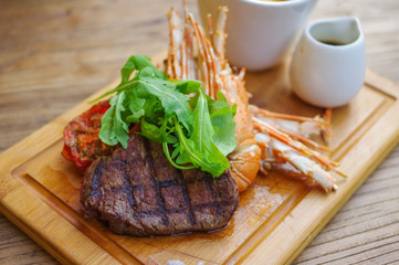 Surf&turf American lobster and steak with french fries on wood tray