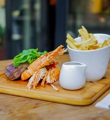 Grilled steak and lobster with french fries on wood plate