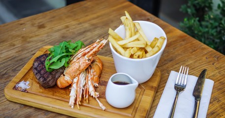 lobster and steak on wooden tray with french fries