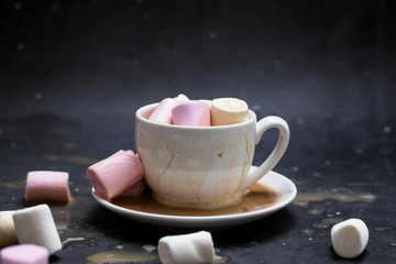 a cup of coffee with marshmallow on dark background