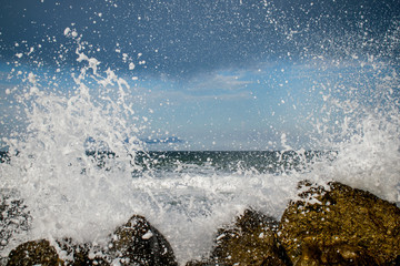 the storm begins at sea. the waves hit the rocks and the water is scattered. a sky covered with...