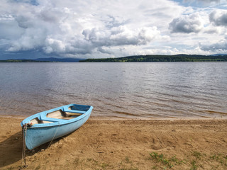Fototapeta na wymiar View to anchored laminate blue rowing boat at large lake
