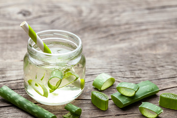 Aloe Vera green cocktail for healthy body and body. Aloe pulp slices in a glass jar and leaves on a wooden table