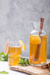Kombucha or cider fermented drink. Cold tea beverage with beneficial bacteria, cinnamon, lemon on concrete  background side view with copyspace. For healthy nutrition.