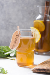 Kombucha or cider fermented drink. Cold tea beverage with beneficial bacteria, cinnamon, lemon on concrete  background side view with copyspace. For healthy nutrition.