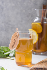 Kombucha or cider fermented drink. Cold tea beverage with beneficial bacteria, cinnamon, lemon on concrete  background side view with copyspace. For healthy nutrition.