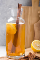 Kombucha or cider fermented drink. Cold tea beverage with beneficial bacteria, cinnamon, lemon on concrete  background side view with copyspace. For healthy nutrition.