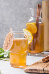 Kombucha or cider fermented drink. Cold tea beverage with beneficial bacteria, cinnamon, lemon on concrete  background side view with copyspace. For healthy nutrition.