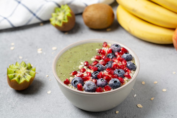 Green smoothie bowl with banana, kiwi, blueberry, granola and pomegranate. Healthy Breakfast detox cocktail in a bowl, vegan food. 