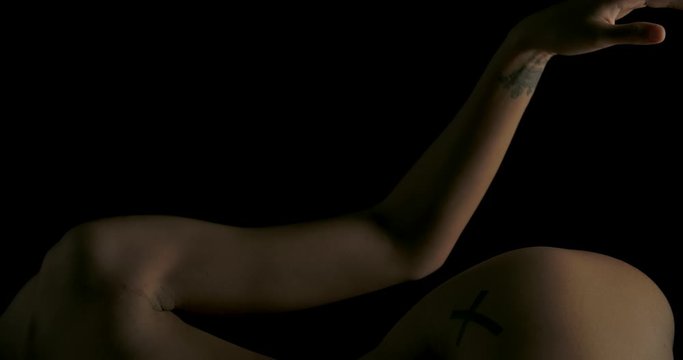 Close-up of Sexy young woman with naked lying and touching herself in low light on black background. Low key silhouette art nude.