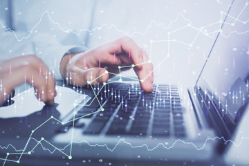 Double exposure of market chart with man working on computer on background. Concept of financial analysis.