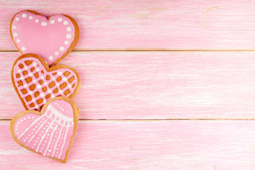 Three Handmade Decorated Heart Shaped Cookies on Pink Wooden Background. Concept of Love, Birthday, Happy Valentine's Day, Merry Christmas. Top View, Copy Space