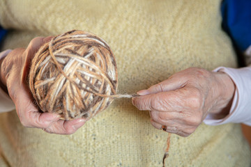Hands of an old woman. Holds a ball of thread. Knitting concept
