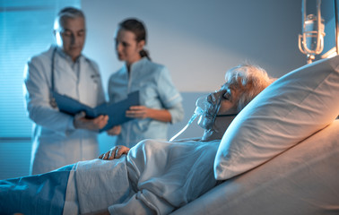 Medical staff discussing and senior patient on a hospital bed
