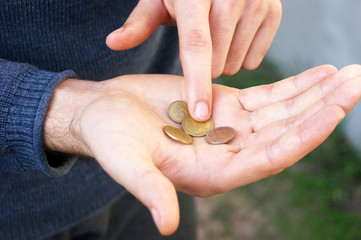 Hands of a young man close-up, counting a trifle, iron coins money of Ukraine.
