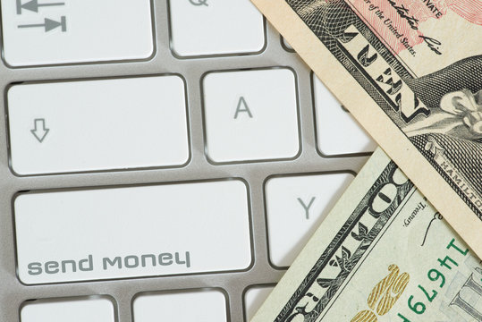 A Computer, Dollar Bills And Button Send Money