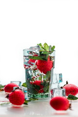 strawberries fall into the water. The freshness of the water. A glass of water and ice.  Fresh strawberries in water. Clean water in a glass. Cocktail with ice.