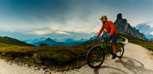 Fototapeta na wymiar Single mountain bike rider on electric bike, e-mountainbike rides up mountain trail. Man riding on bike in Dolomites mountains landscape. Cycling e-mtb enduro trail track. Outdoor sport activity.