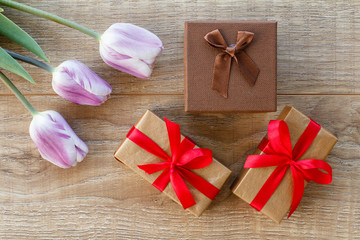Gift boxes with tulip flowers on the wooden background.