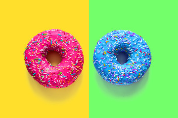 Two glazed doughnuts pink and blue on multicolored backgrounds
