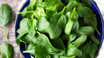 Fresh baby spinach. Washed spinach leaves on a blue plate. Diet concept.