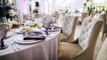 Table set. Beautiful wedding restaurant decoration in purple tones: purple glasses, purple flowers...