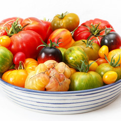 Bunte, exotische,  historische Tomaten Vielfalt, von schwarz bis gestreift, süß und saftig in einer Schale vor weißem Hintergrund presentiert.