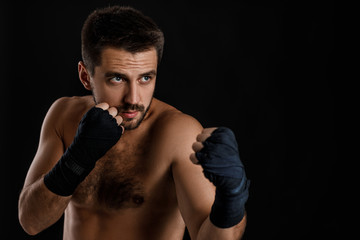 boxer man with bandage on hands training before fight and showing the different movements on black background